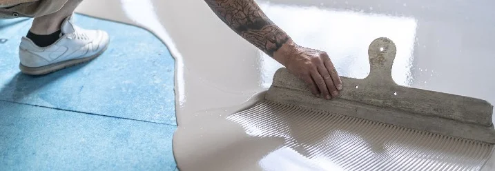 Person verteilt Estrich mit Glätter.